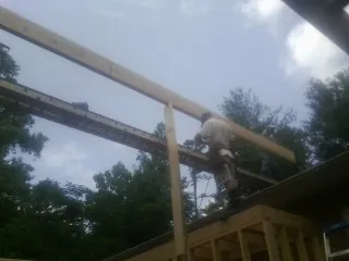 Carpenter setting a ridge beam over a new addition frame — Ice Dam Removal by Roofing Brothers in Bel Alton