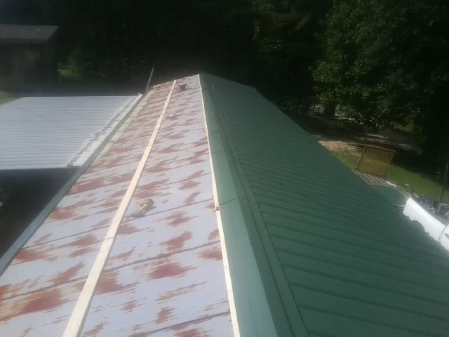 Old rusted panels beside newly installed green metal roofing — Wind Damage Roof Repair by Roofing Brothers in Bel Alton
