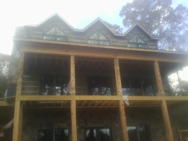Dormers and porch framing on a large log home under construction — Roof Coating work by our crew in Bel Alton