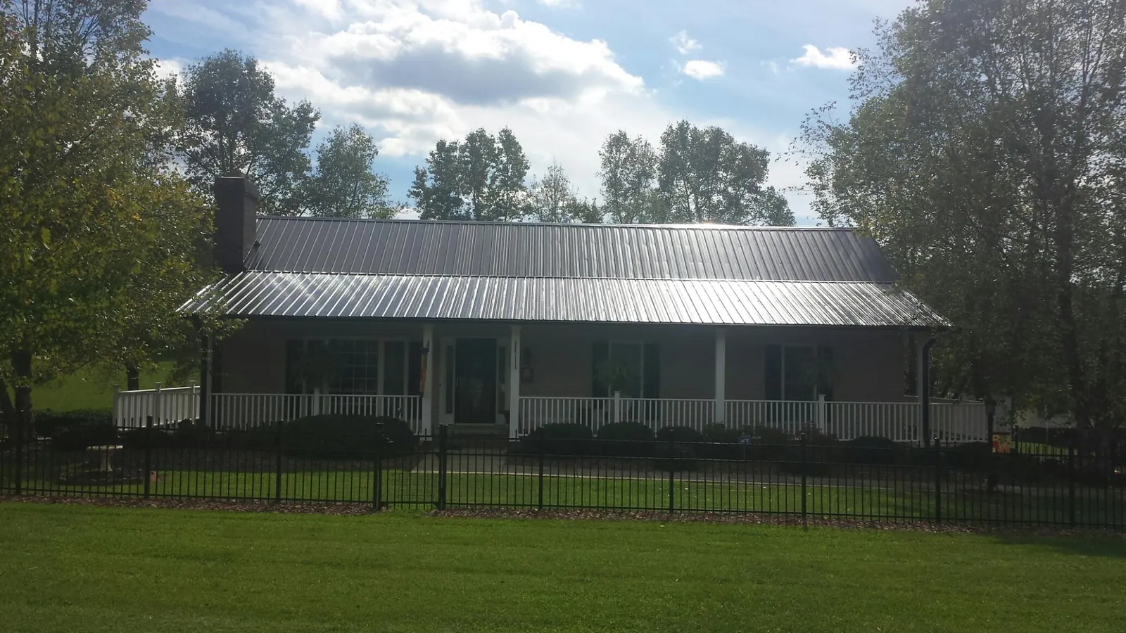 Gray metal roof on a brick ranch with a full width front porch — Gutter Guard Installation work by our crew in Bel Alton