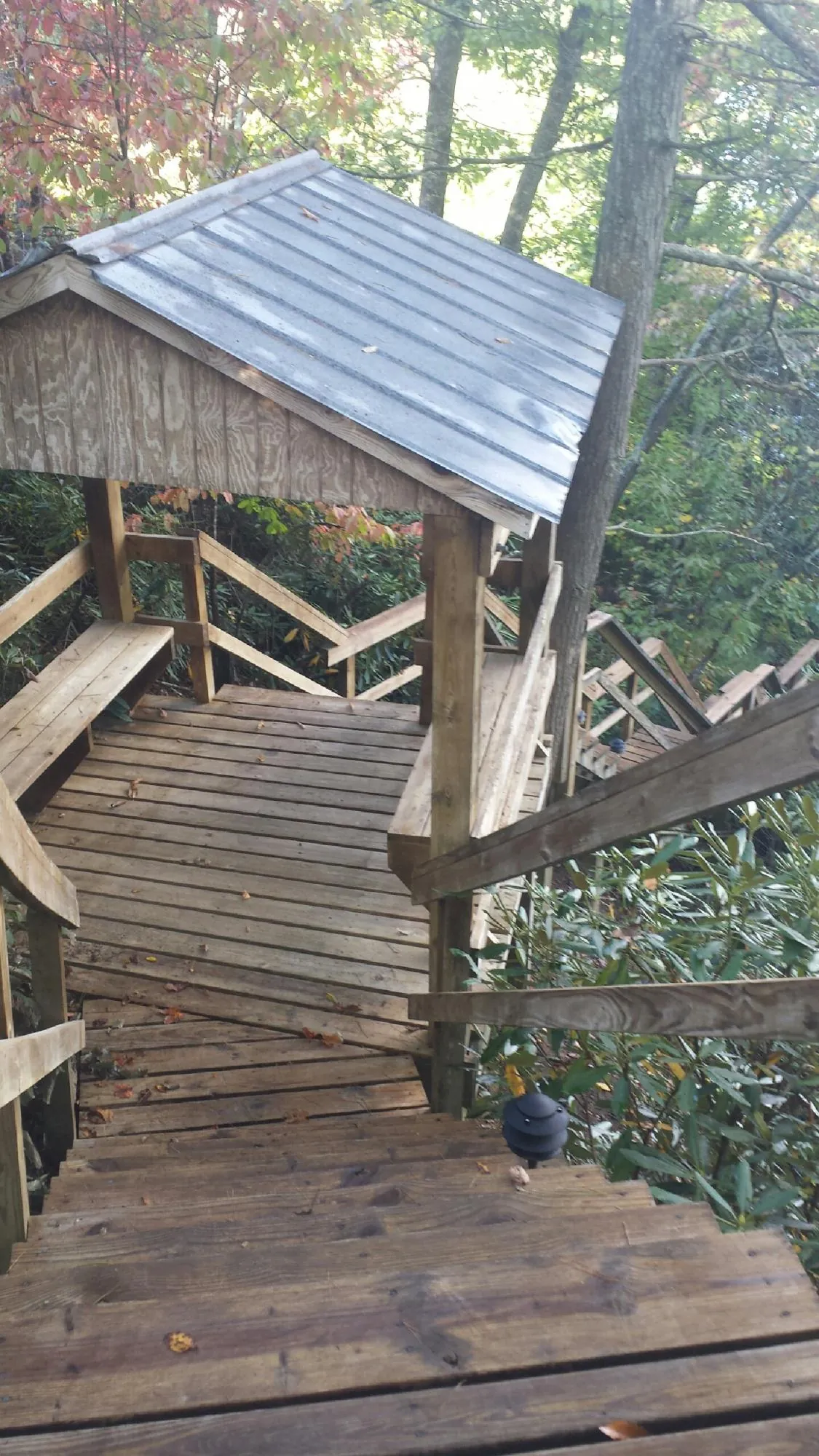 Metal roofed shelter over wooden steps on a wooded walkway — Skylight Repair & Installation work by our crew in Bel Alton