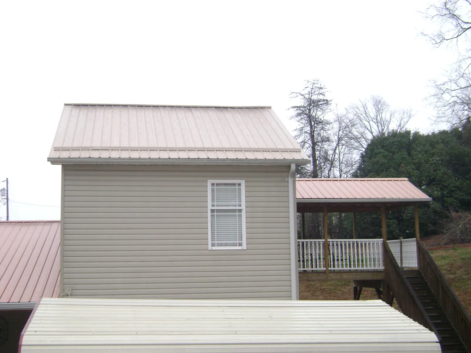 Tan metal roofs on a two story addition and attached porch, from a Roof Replacement job in Bel Alton