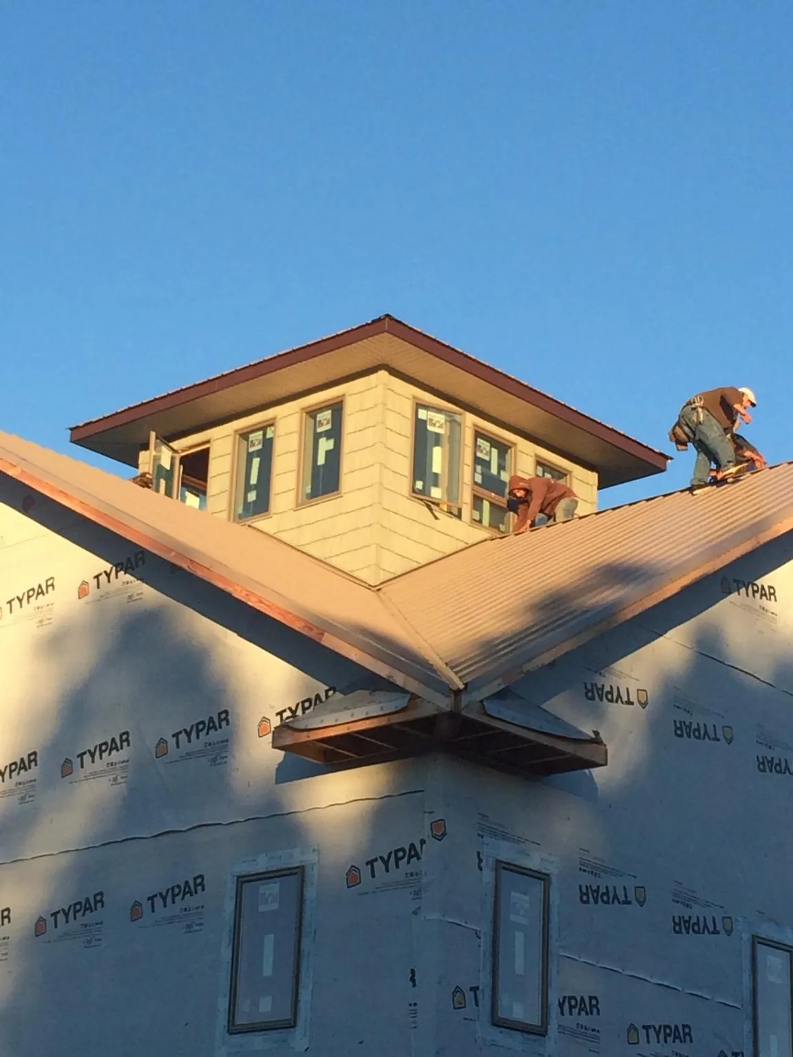 Roofers working around a rooftop cupola on a new metal roof at sunset — Roof Waterproofing in Bel Alton by Roofing Brothers